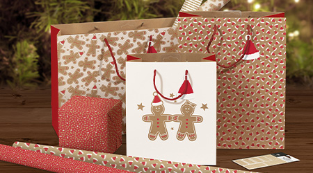 Weihnachts-Geschenktaschen und Geschenkpapier aus Kraftpapier mit Lebkuchenmännern von Clairefontaine vorm Weihnachtsbaum.