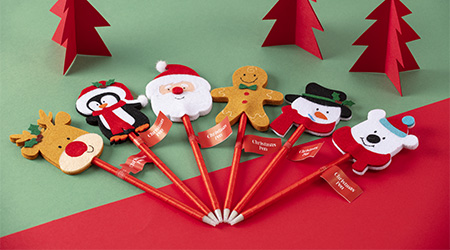 Stifte mit Weihnachtsobjekt in Halbkreis von Clairefontaine. Liegen auf rot-grünem Hintergrund.