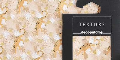 Gemustertes Décopatch-Papier mit Illustrationen von Leoparden und tropischen Blättern in Beige und Weiß, gekennzeichnet als „TEXTURE“ von Décopatch. Das Papier zeigt ein sich wiederholendes Muster aus Leoparden und Blättern auf einem weichen Hintergrund.