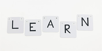 Weiße Sticker mit schwarzen Buchstaben „LEARN“ auf weißem Hintergrund.