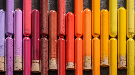 Liegende Reagenzgläser mit Pigmenten von Blockx. Verschiedene Farben: Lilatöne, Rottöne, Orangetöne, Gelbtöne.