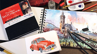 Tisch mit Skizzenbuch Mixed Media Alpha von Stillman&Birn, schwarzer Einband. Mit Stiften und Farbe. Offene Skizzenbücher mit Zeichnung eines roten Autis und einer Kleinstadt.