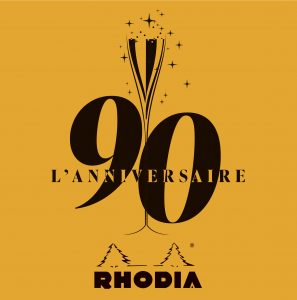 Orangenes Logo 90 Jahre Rhodia mit gezeichnetem Champagnerglas und Sternen in Schwarz.