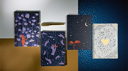 Notizhefte mit Doppelspirale der Kollektion Adolie von Clairefontaine. Blauer Hintergrund mit astralen Motiven.