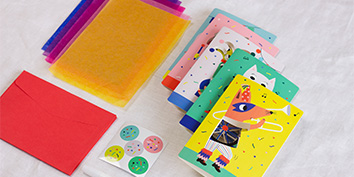 Bunte Grußkarten mit Tiermotiven, Seidenpapierbögen, einem roten Umschlag und runden Aufklebern.