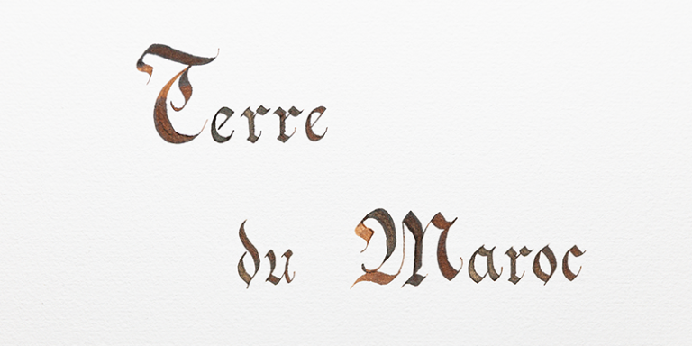 Text Terre du Maroc mit ockerfarbener Tinte mit Goldschimmer geschrieben.